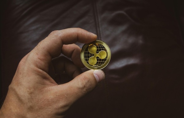 Hand holding a gold Ripple (XRP) branded coin